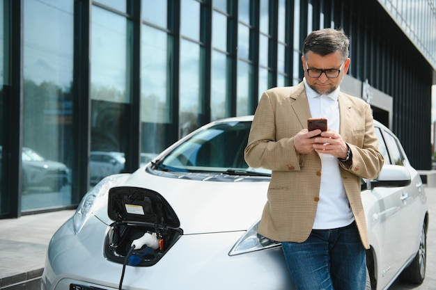 Um empresário carrega um carro elétrico