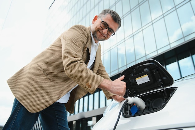 Um empresário carrega um carro elétrico