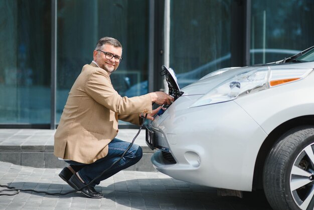 Um empresário carrega um carro elétrico