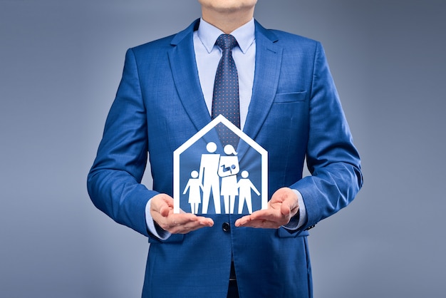 Um empresário de terno azul mantém uma casa com sua família na frente dele