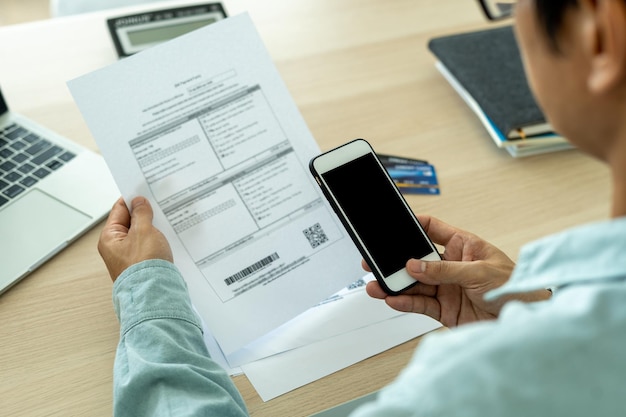 Foto um empresário do sexo masculino usando um telefone inteligente para digitalizar um código de barras para pagar contas telefônicas mensais após receber faturas conceito de pagamento de contas online