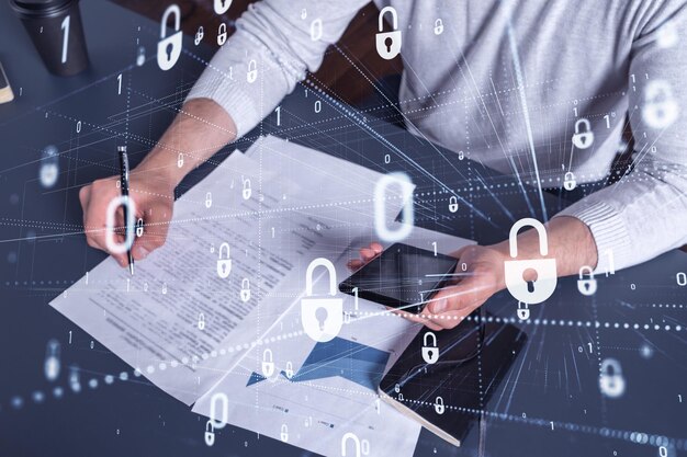 Um empresário em roupas casuais assinando o contrato para evitar a probabilidade de riscos na segurança cibernética Verificando os ícones de holograma de cadeado do telefone sobre a mesa de trabalho