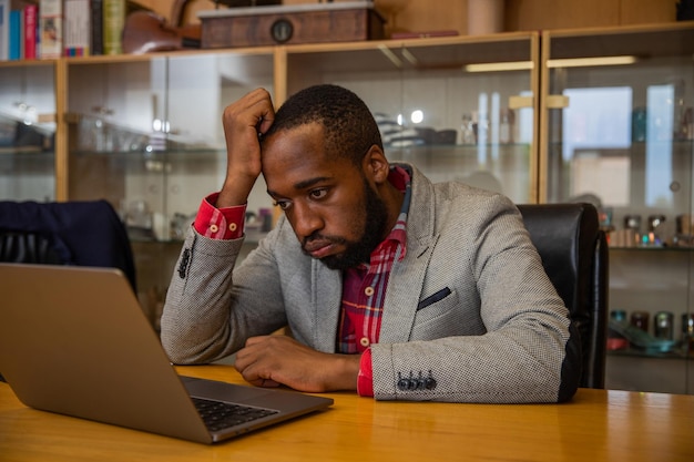 Um empresário está triste e zangado enquanto está no escritório olhando para a tela do laptop