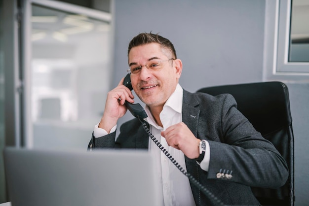 Um empresário feliz tendo telefonema de negócios do escritório moderno