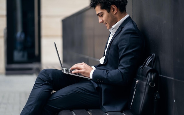 Um empresário masculino está usando um laptop em um terno de negócios trabalhando