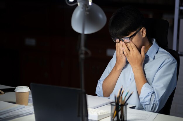 Um empresário que trabalha horas extras no escritório cansa os olhos.