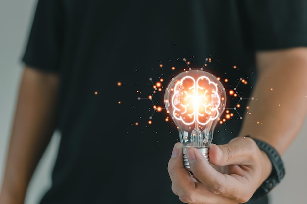 Um empresário segura uma lâmpada com um cérebro virtual brilhante, uma linha de conexão e um conceito de rede para pensamento inovador e criativo