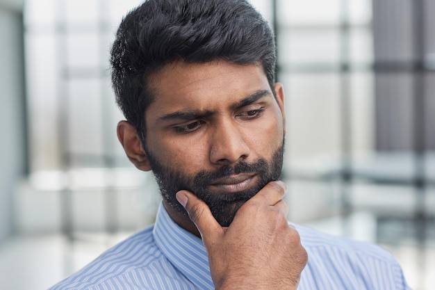 Um empresário sênior ou gerente com barba pensando enquanto coça o queixo tentando ter uma ótima ideia