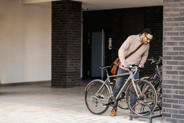 Um empresário urbano está estacionando sua bicicleta na rua em frente ao seu local de trabalho