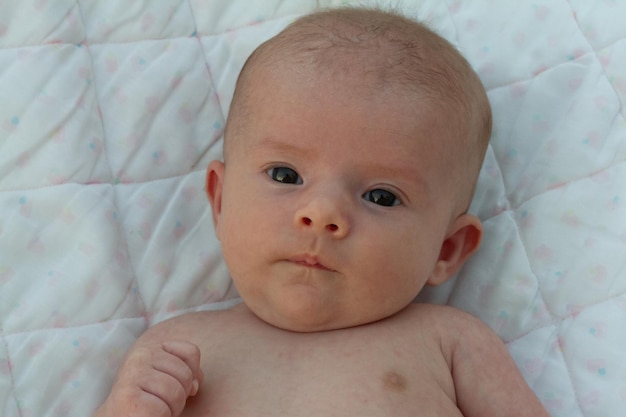 um encantador bebê recém-nascido de dois meses descansa relaxado em seu berço depois de um banho