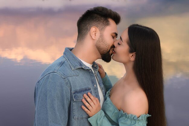 Um encontro romântico Um belo casal a beijar-se perto do lago