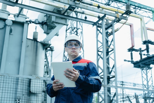 Um engenheiro de energia inspeciona o equipamento moderno de uma subestação elétrica antes do comissionamento Energia e indústria Reparo programado de equipamentos elétricos