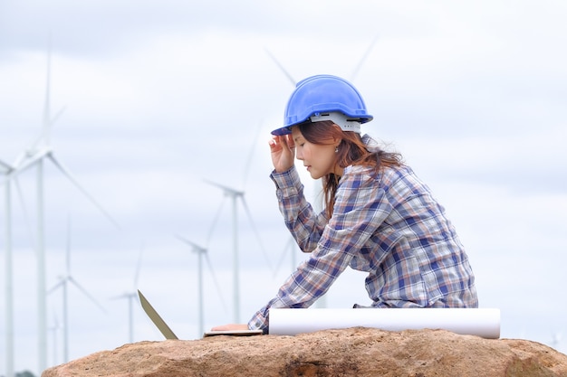 Foto um engenheiro está sentado em seu laptop olhando para um projeto de turbina eólica de energia limpa para gerar eletricidade.