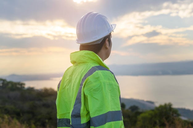 Um engenheiro homem está colocando um capacete protetor na cabeça ao pôr do sol.