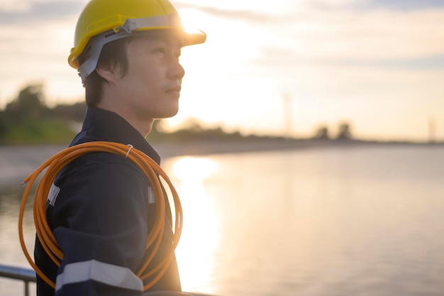 Um engenheiro masculino usando um capacete protetor ao pôr do sol.