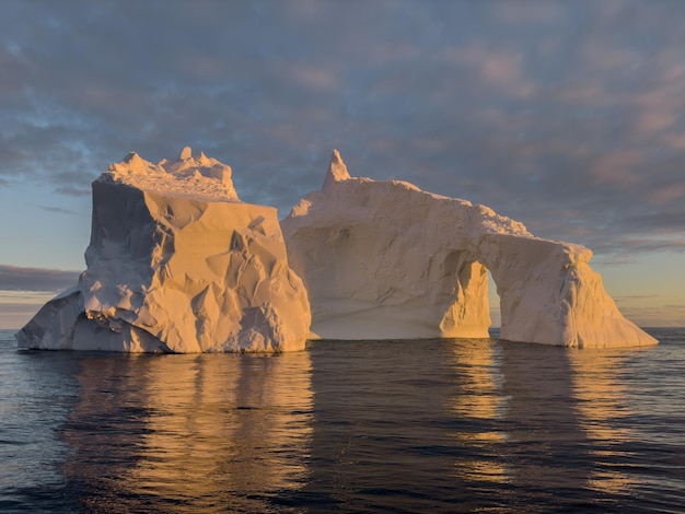 Um enorme glaciar desprendido deriva no oceano sul ao largo da costa da Antártida ao pôr-do-sol.