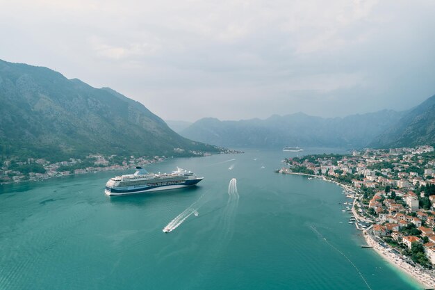 Um enorme navio de cruzeiro navega ao longo da baía de Kotor passando pela costa de Montenegro.
