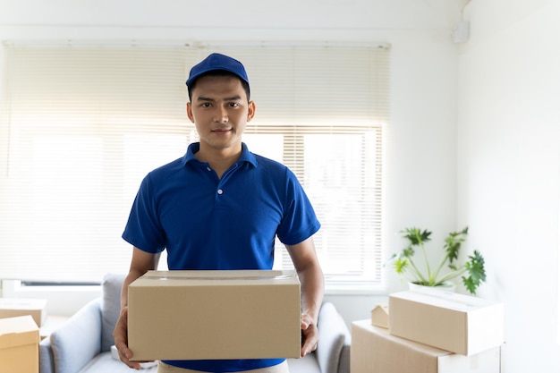 Um entregador masculino de camisa azul e chapéu está carregando mercadorias para entregar clientes aos seus destinos