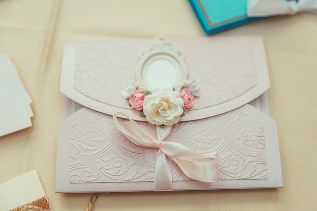 Um envelope com relevo rosa suave decorado com uma fita rosa claro rosas artificiais