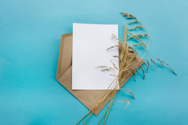 Um envelope de papel kraft com um cartão branco em branco sobre fundo azul Preparação de cartões postais