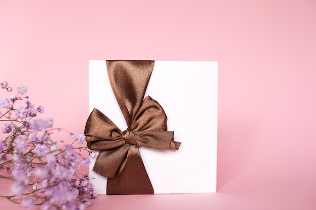 Um envelope de presente com um laço com um espaço de cópia vazio em um fundo rosa Flat fica gypsophila