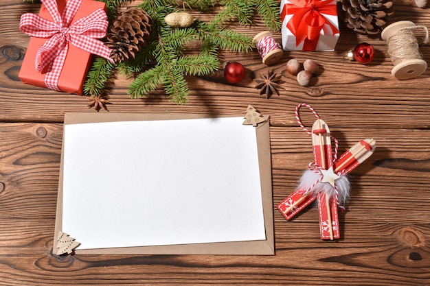 Um envelope e uma folha de papel em branco em uma folha de madeira com enfeites de natal.