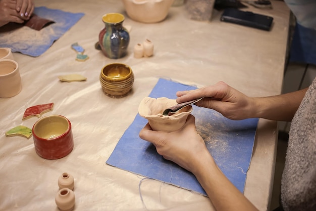 Um escultor humano faz um produto de barro com as próprias mãos