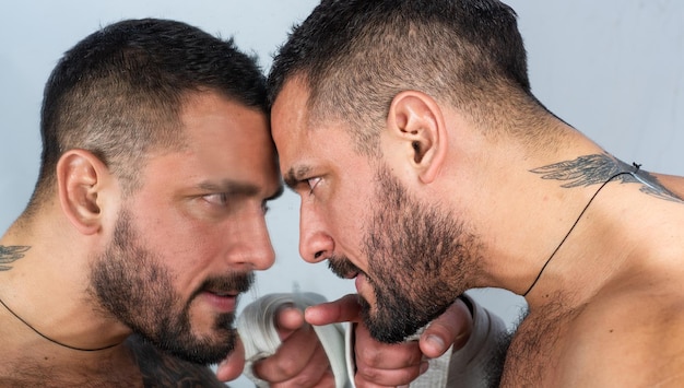 Foto um espelho onde um homem se observando homem e espelho homem hispânico barbudo apontando o dedo no espelho homem latino brutal com barba e bigode olhando seu reflexo no espelho