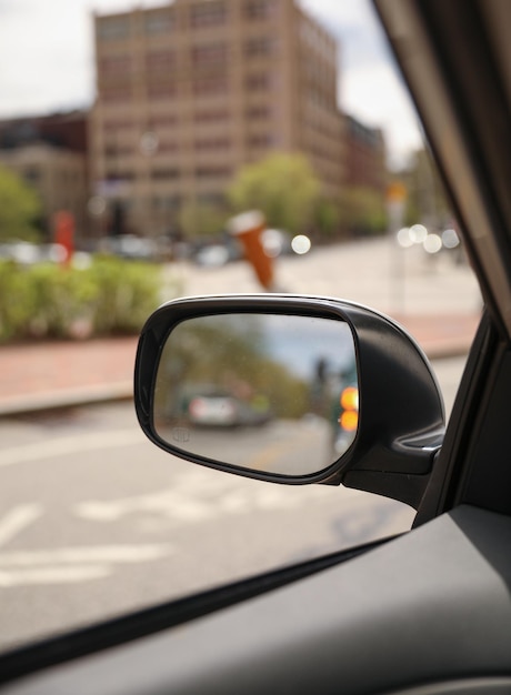 Um espelho retrovisor mostra um carro com uma luz vermelha na lateral.