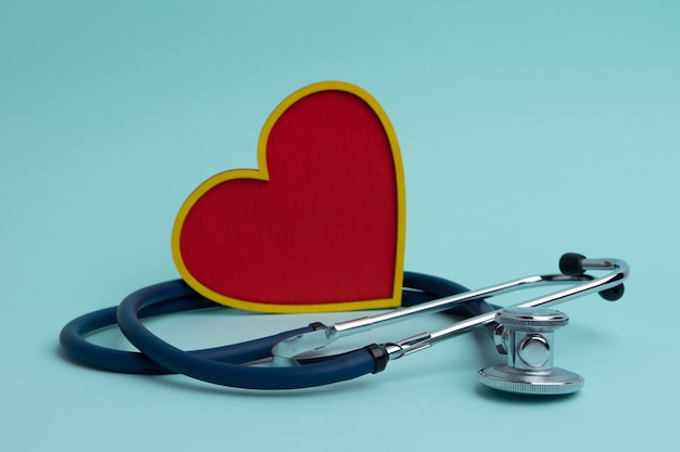 Um estetoscópio e um coração vermelho sobre um fundo azul. o conceito de cardiologia.