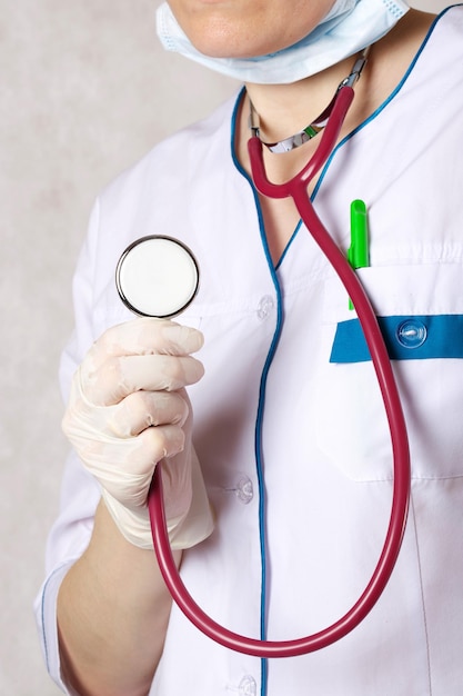 Um estetoscópio nas mãos de um médico vestido com um uniforme profissional branco