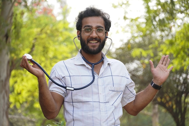 Um estudante animado mostrando o estetoscópio - estudante universitário com estetoscópio e mostrando o sinal de sucesso - conceito de educação médica