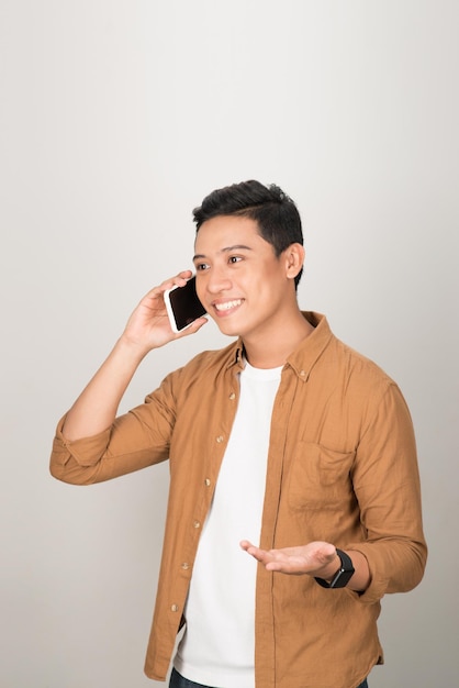 Um estudante asiático bonito pegando o celular isolado no fundo branco