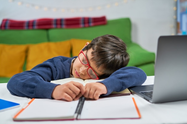 Foto um estudante cansado dormindo na mesa enquanto faz a lição de casa, o interior da casa