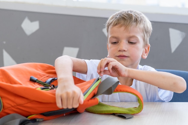 Um estudante coloca papel de carta em uma mochila Uma criança fecha uma mochila escolar De volta à escola