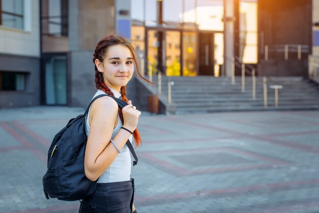 Um estudante do ensino médio com uma mochila fica no pátio da Universidade