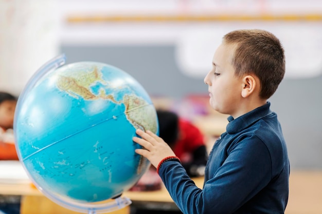 Um estudante procurando lugares no globo na aula de geografia