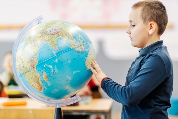 Um estudante respondendo a perguntas sobre a aula de geografia e tocando o globo