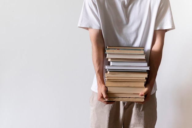 Um estudante segurando e carregando uma pilha de livros