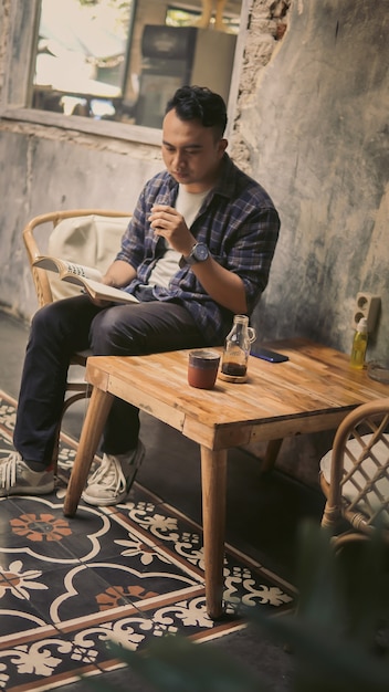 Um estudante tomando café enquanto lê um livro à tarde