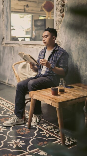 Um estudante tomando café enquanto lê um livro à tarde