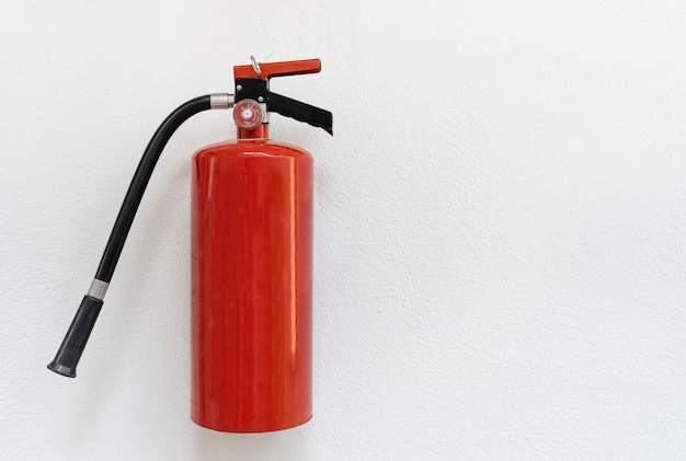 Um extintor de incêndio vermelho na parede branca, copie o espaço