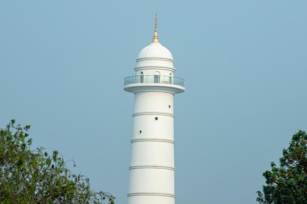 Um farol branco com topo dourado e topo dourado.