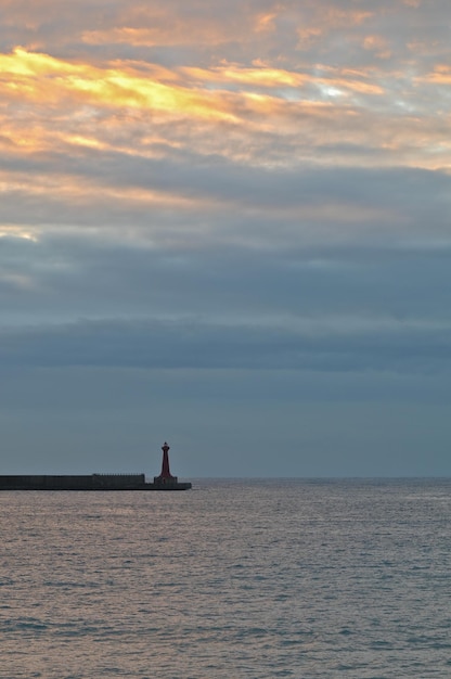 Um farol e o mar calmo no início da manhã