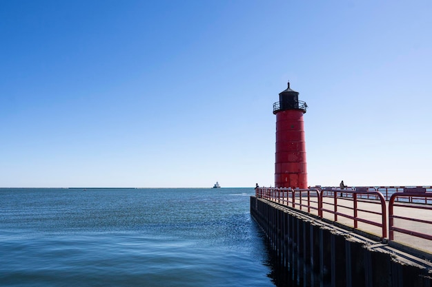 Um farol no cais com um céu azul ao fundo.