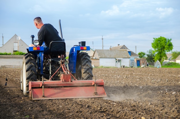 Um fazendeiro em um trator limpa o campo após a colheita preparação da terra para plantio futuro