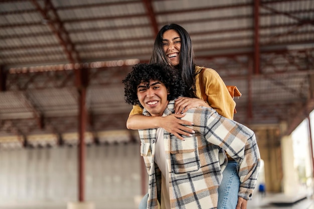 Um feliz casal multicultural apaixonado está andando de cavalinho na rua da cidade