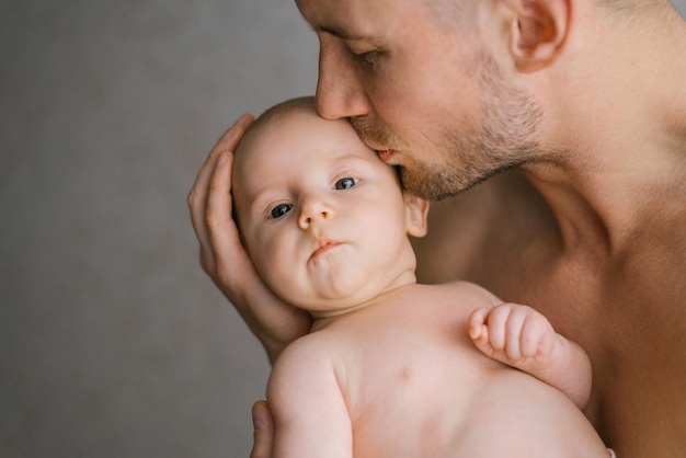Um feliz pai caucasiano segura seu filho bebê nos braços e o beija com cuidado