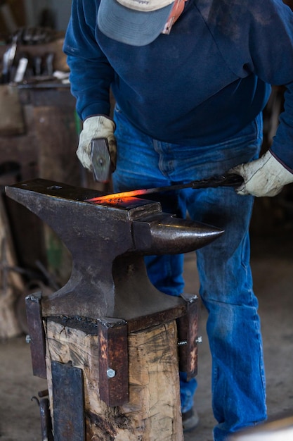 Um ferreiro forjando ferro quente na bigorna.