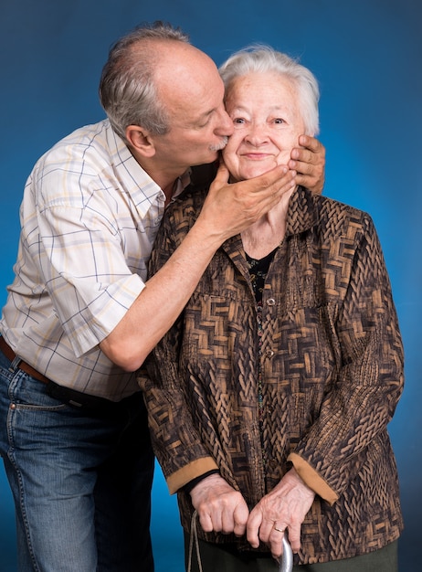 Um filho adulto beijando sua mãe idosa posando